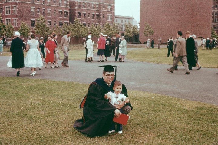 author of this post in cap and gown holding a young son in his arms