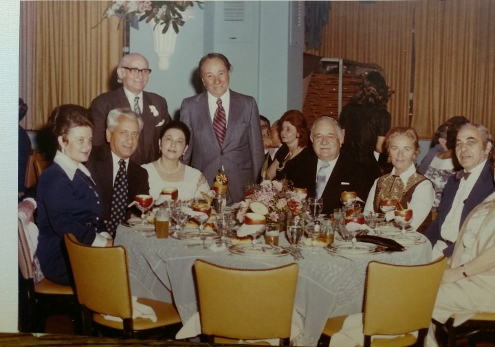 many people around a restaurant table enjoying a social coccasion