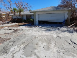 Muck in the driveway, garage door damaged, trees fallen in the yard