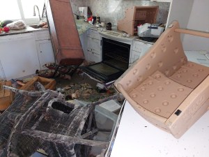 Damage to kitchen with furniture junking up the floor and window and the oven door opened